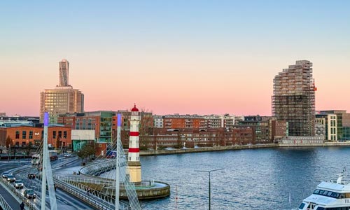 Himmel med aftonrodnad i en stad vid vattnet